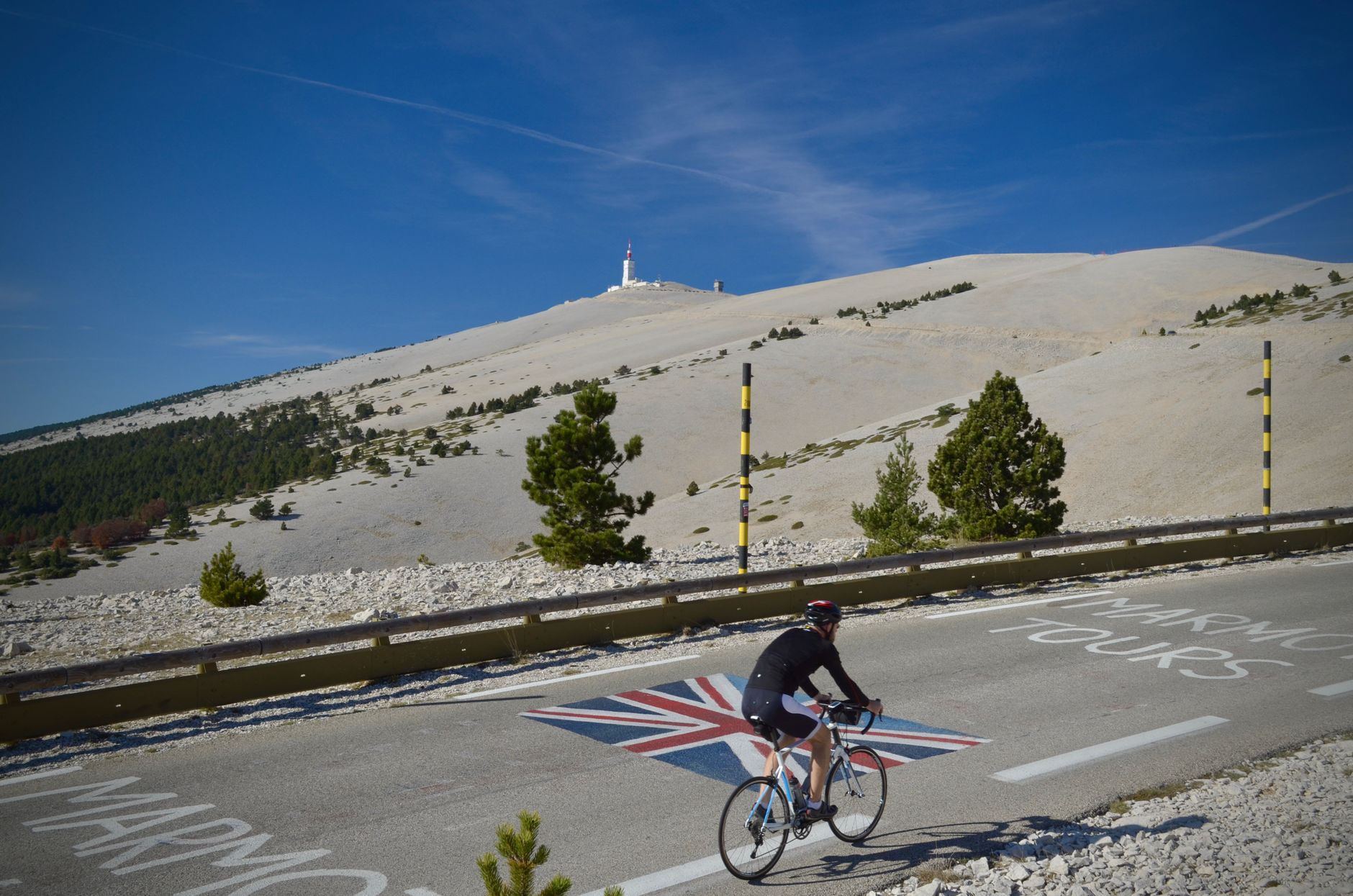 Cyclist climbing Mont Ventoux in Vaucluse, France, under clear blue skies, capturing the essence of Tour de France.