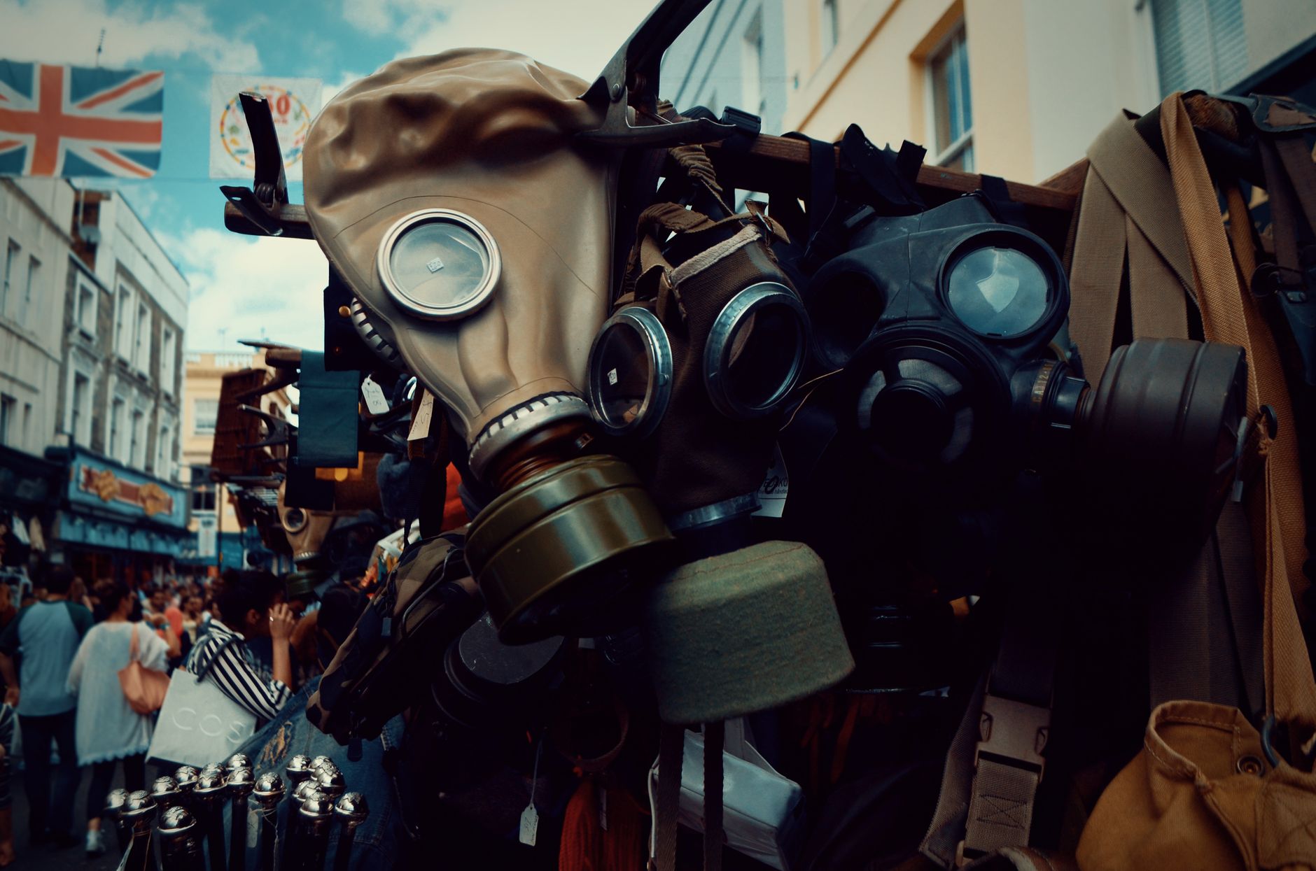 A vibrant display of vintage gas masks at a bustling outdoor market, showcasing diverse military gear.