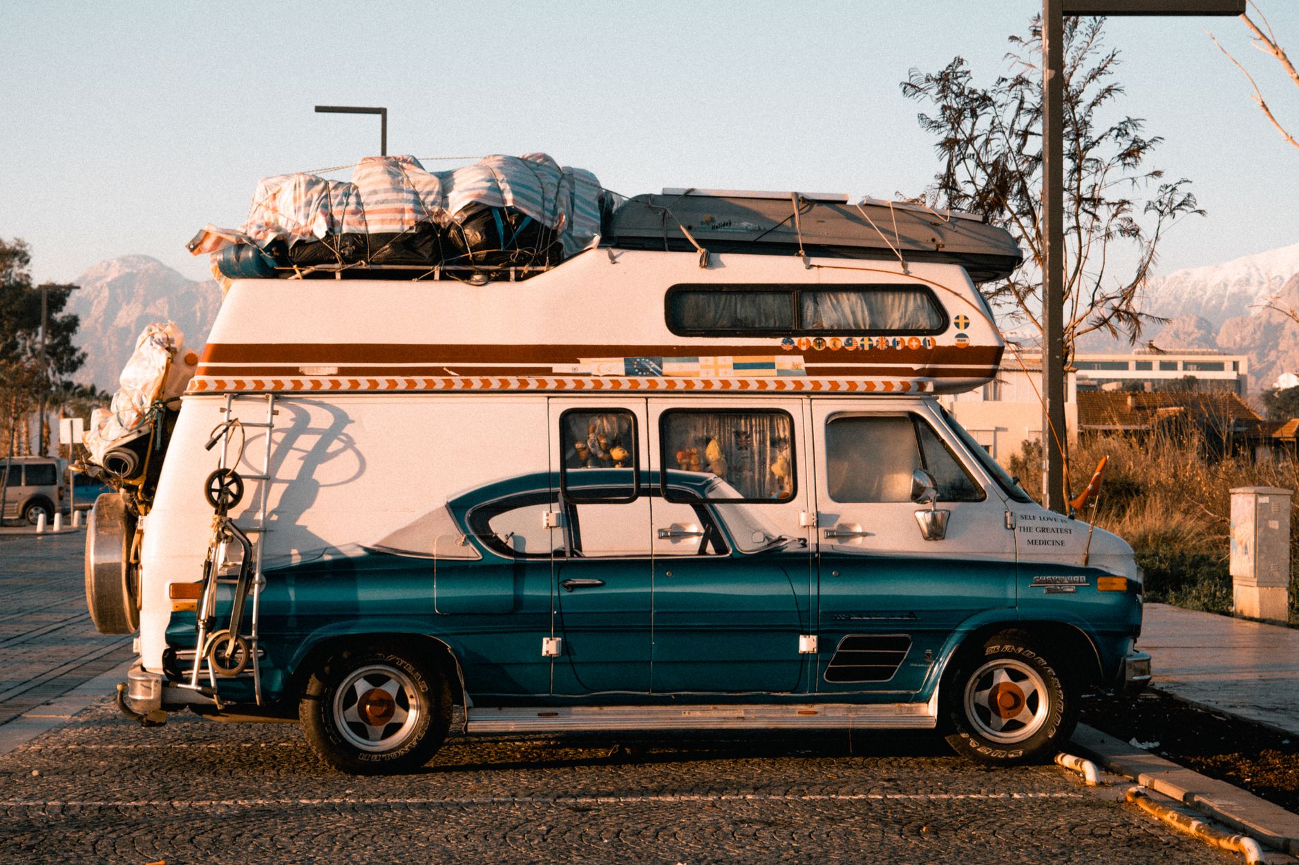 Retro camper van loaded for adventure, basking in warm sunset lighting.