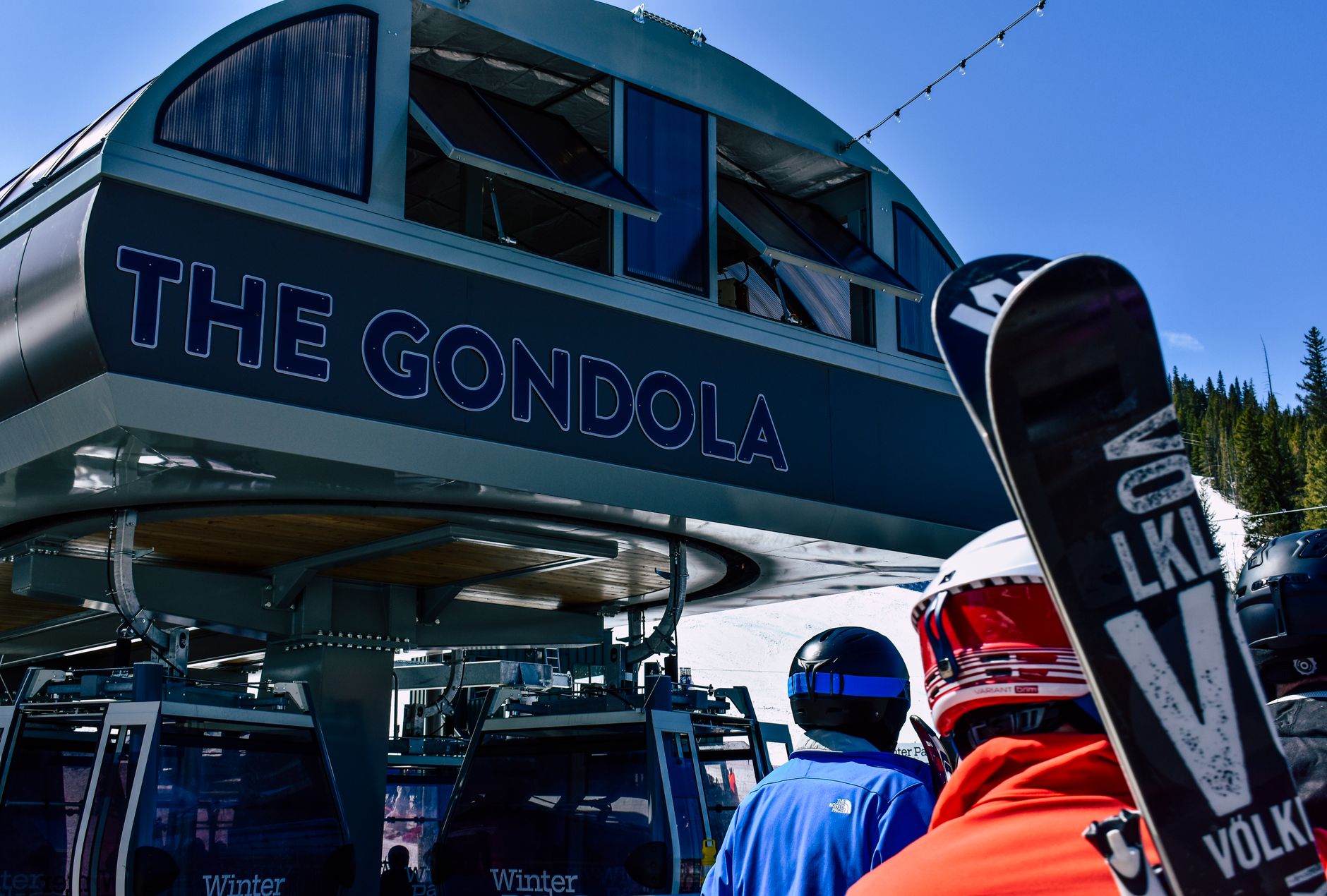 Skiers wait at the gondola station for skiing and snowboarding adventures in winter mountains.