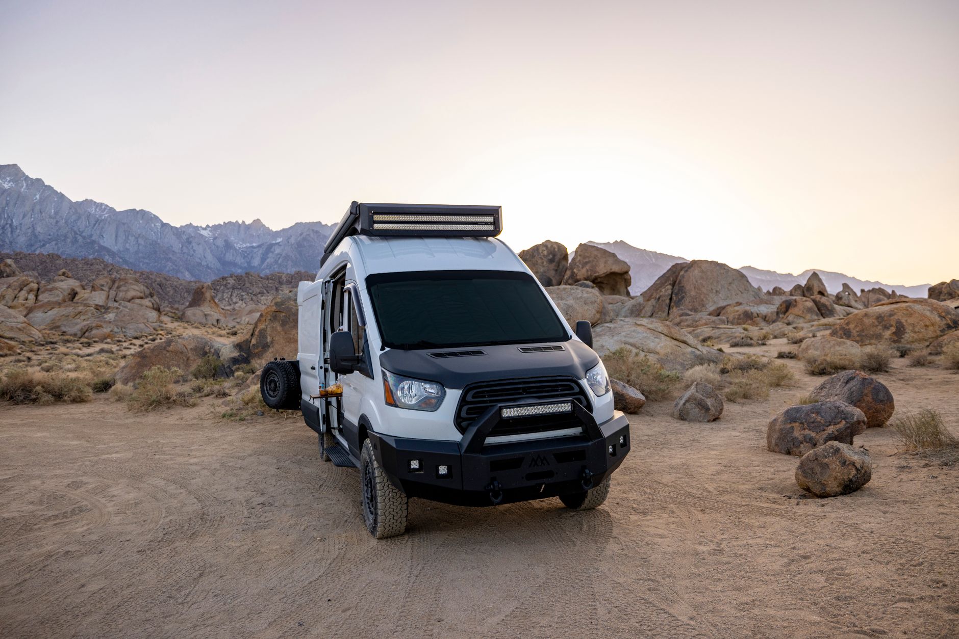 An off-road camper van parked in a rocky desert landscape during daytime.