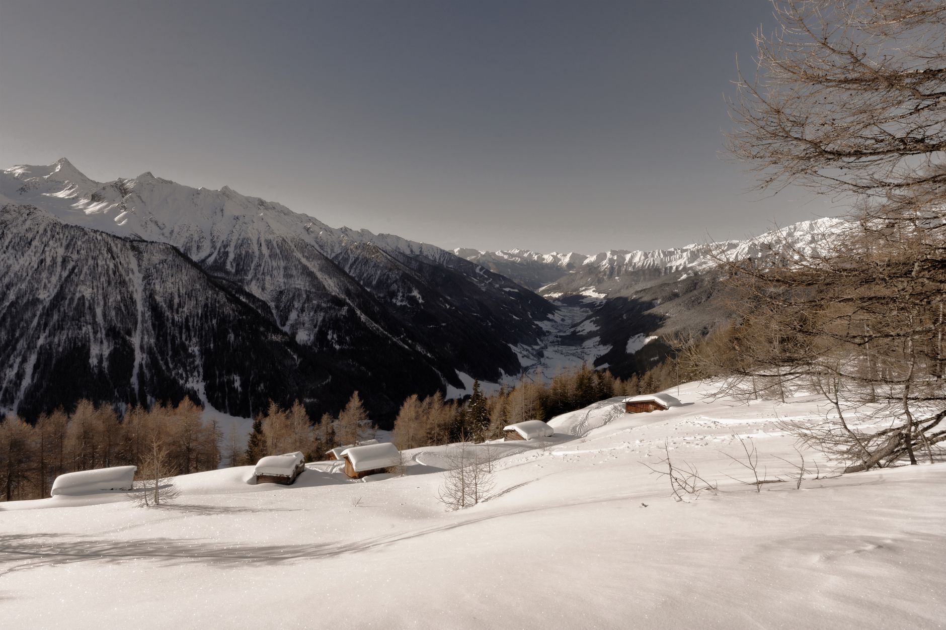 Scenic winter view of snow-covered cabins in a serene Alpine mountain setting.