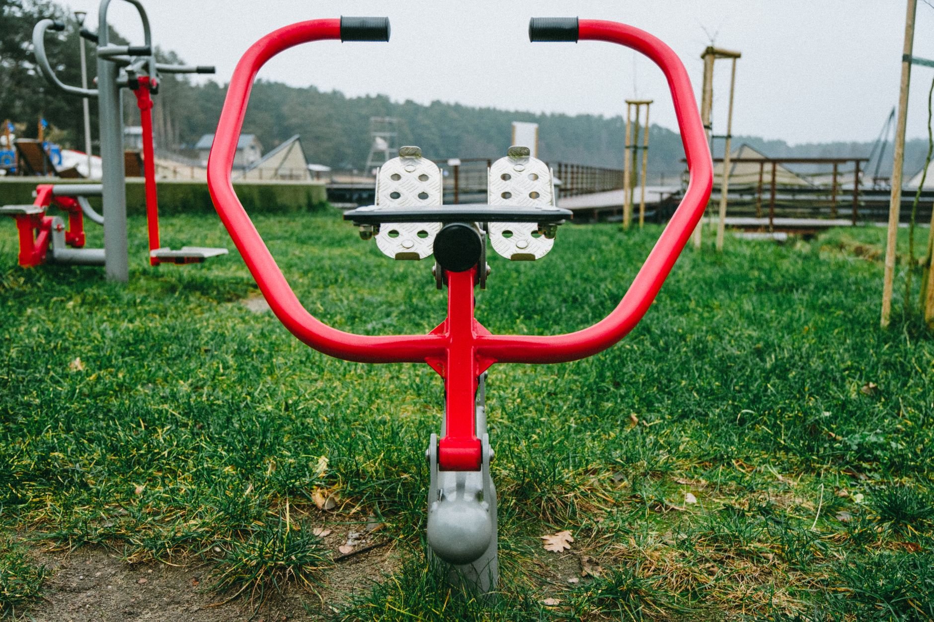 Red outdoor exercise equipment in a park setting in Poland, surrounded by grass, perfect for fitness enthusiasts.