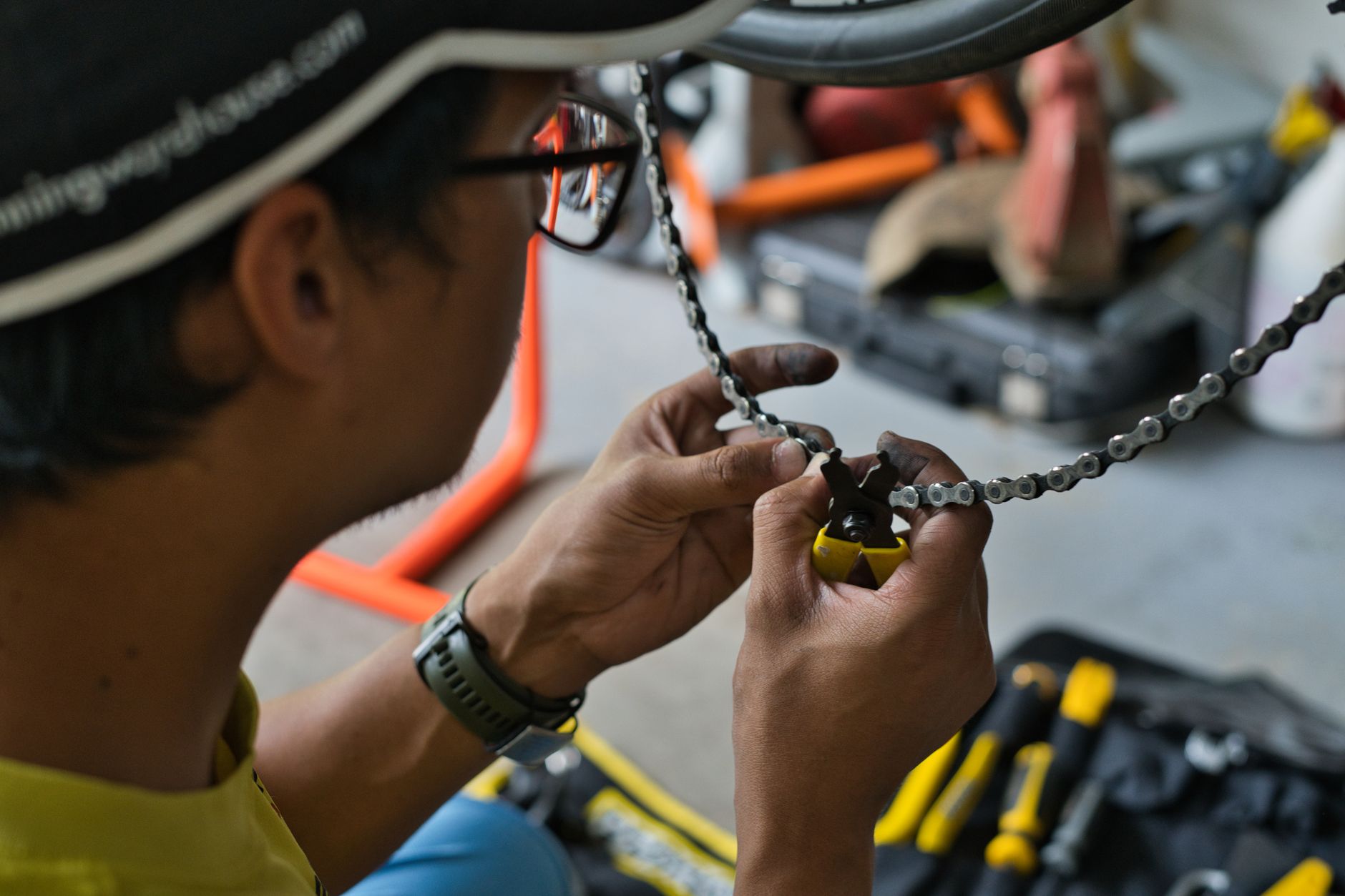 Close-up of a mechanic working on a bicycle chain inside a workshop, showcasing precision and manual skill.