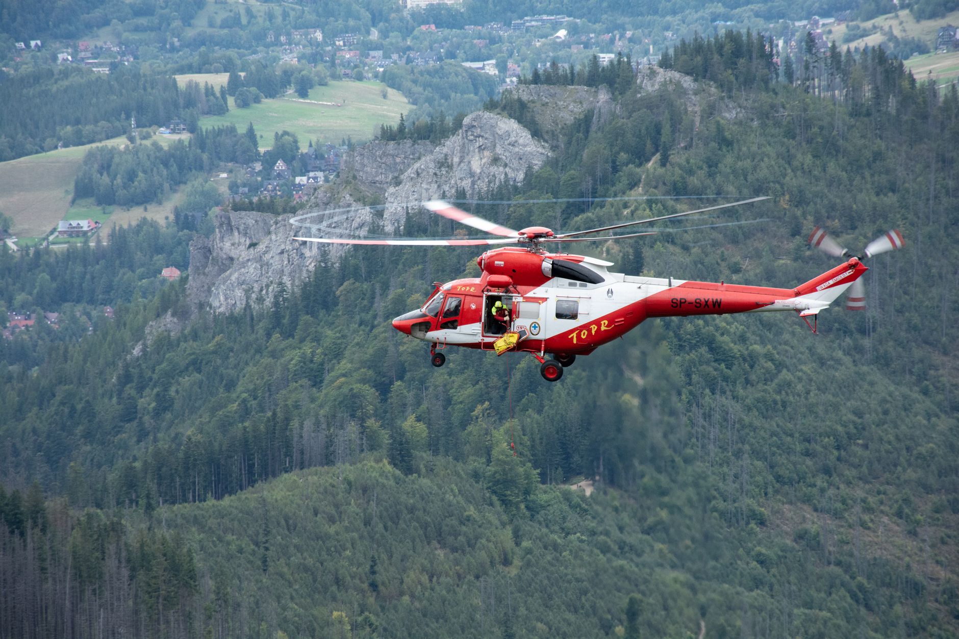 A rescue helicopter flying over the scenic Tatry mountains in Poland.