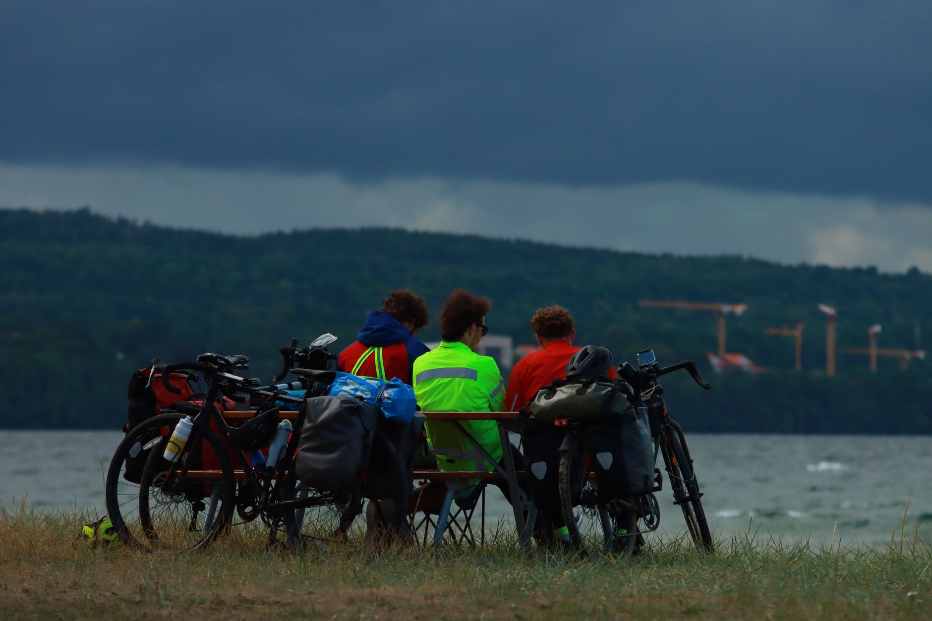 Group of cyclists relaxing by a lake in Jönköping, Sweden during a cloudy day.