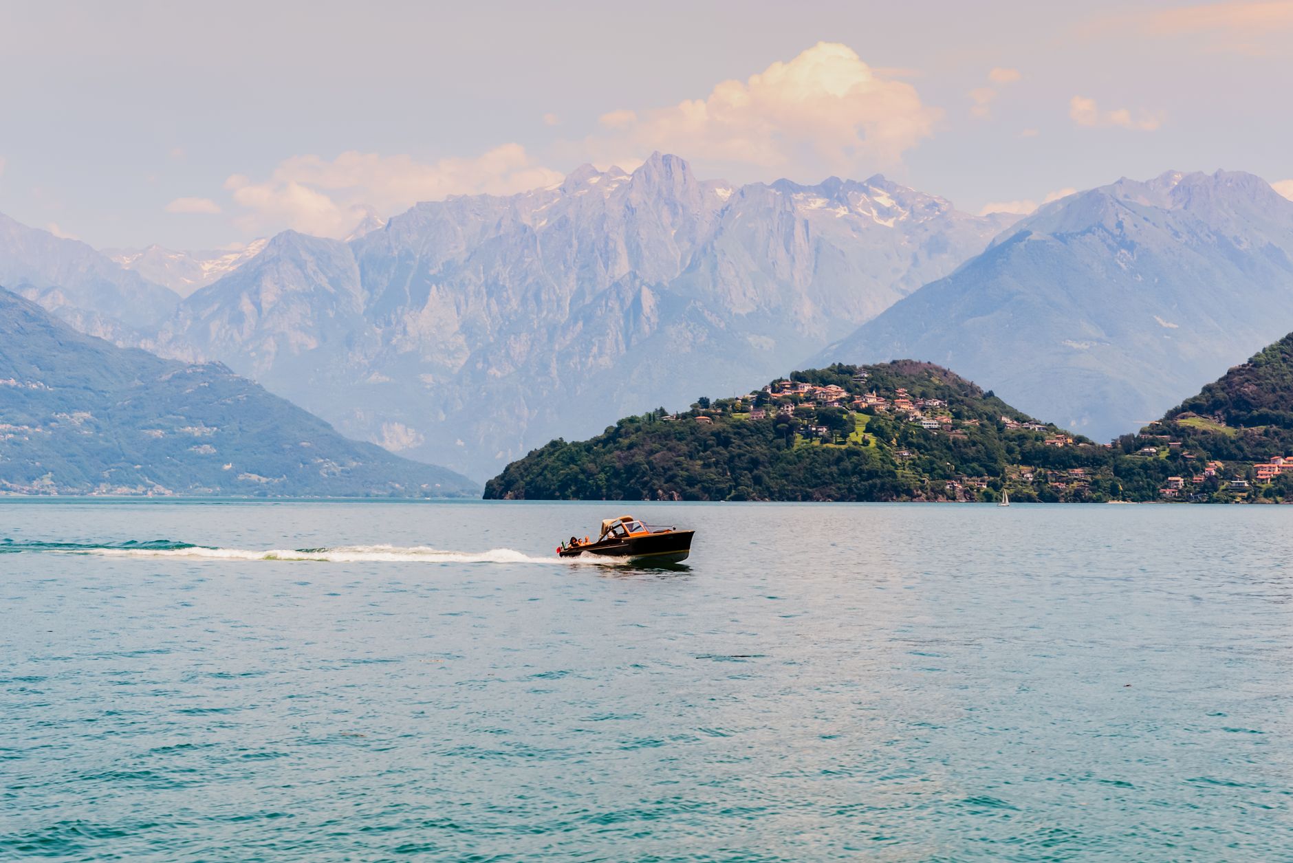 A motorboat cruising on Lake Como with stunning mountainous backdrop in Lombardy, Italy.