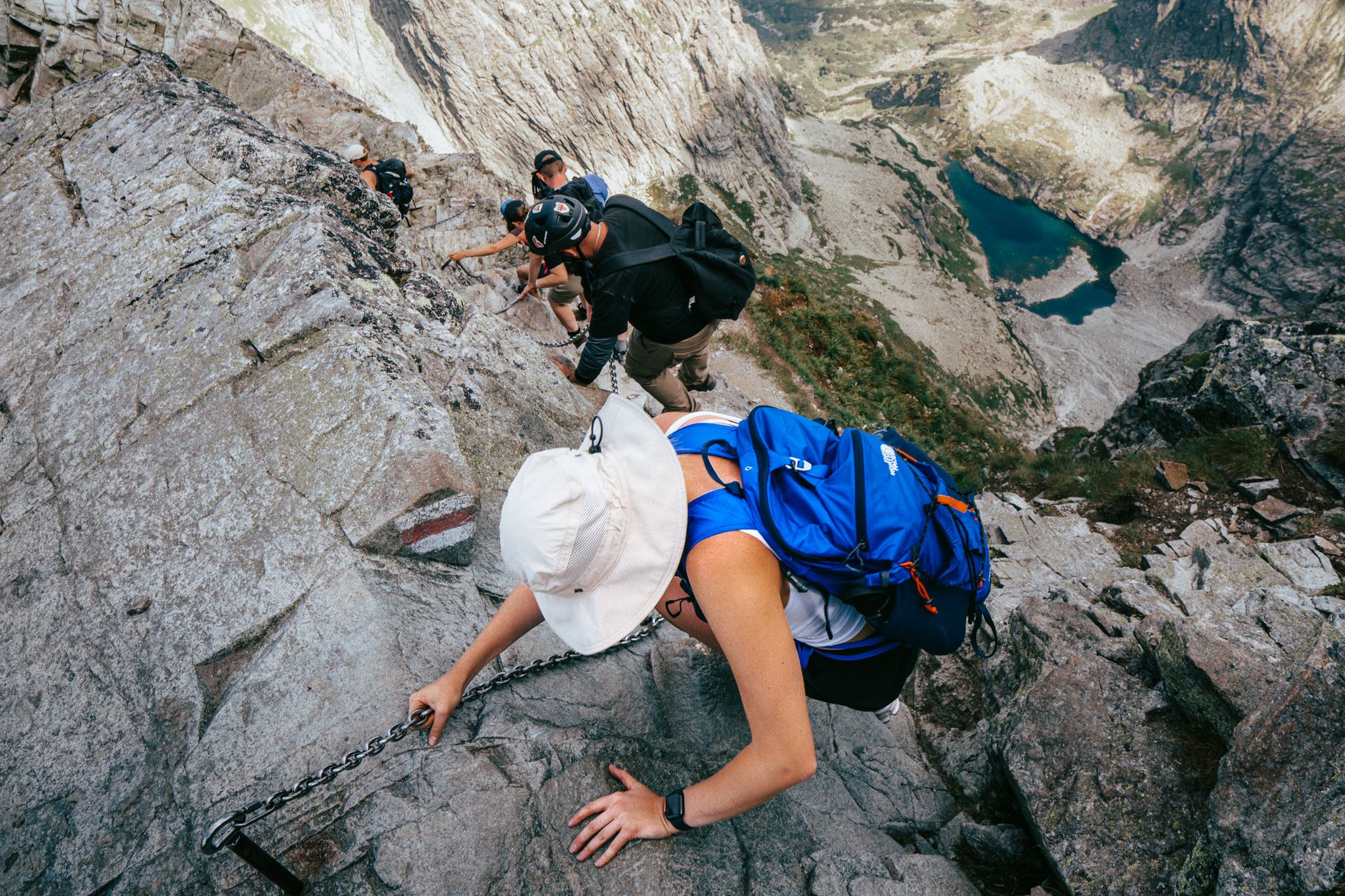 Adventurous hike on a rocky trail in High Tatras, showcasing an alpine lake and mountain scenery.