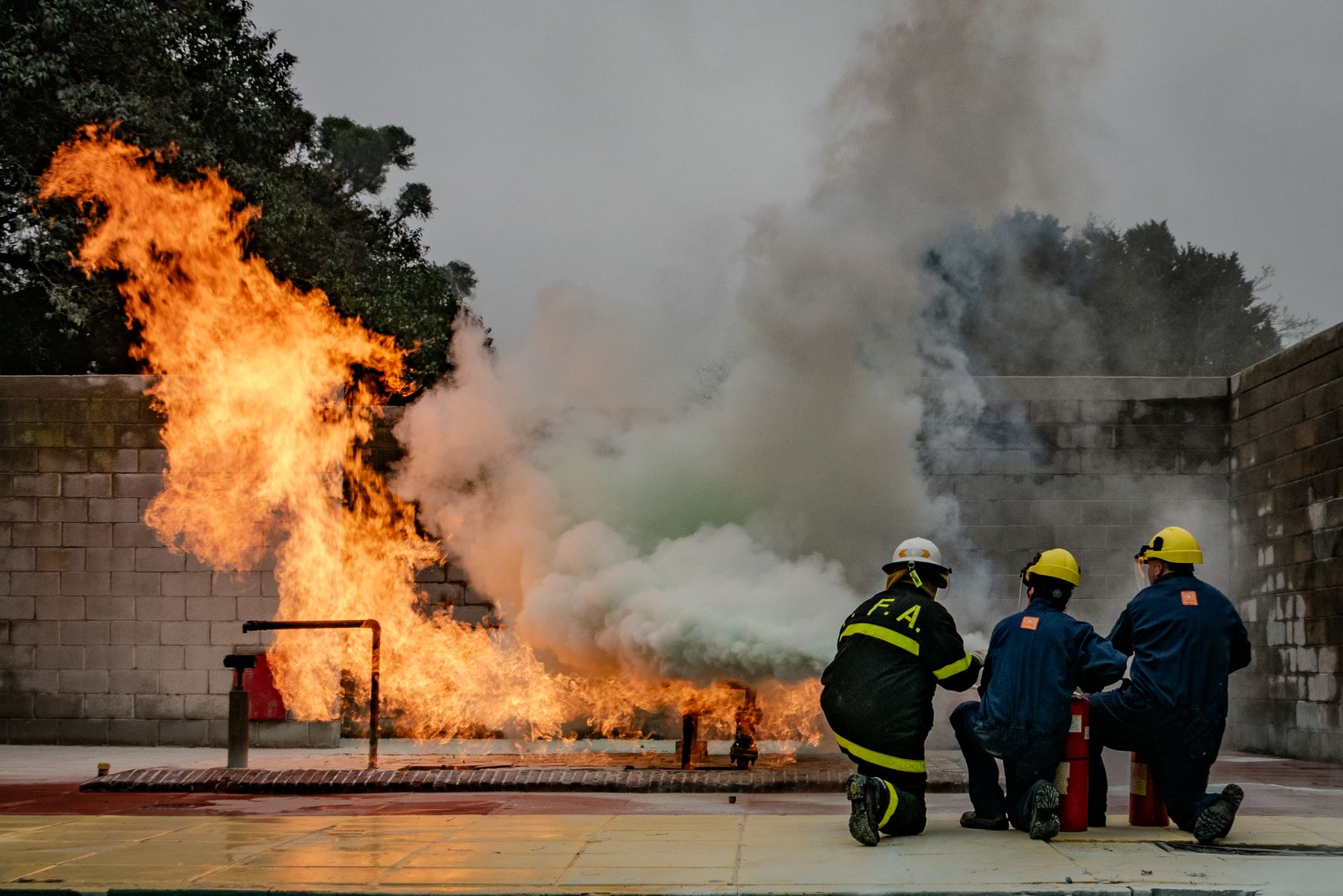 Firefighters in training combat a controlled blaze during a safety drill, emphasizing teamwork and skill.