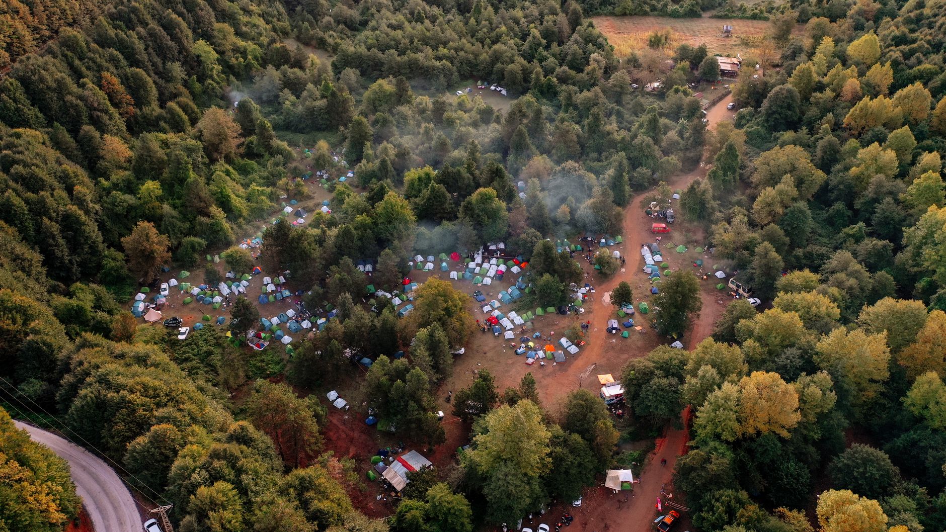 Drone shot capturing a vibrant campsite nestled within a dense forest setting.