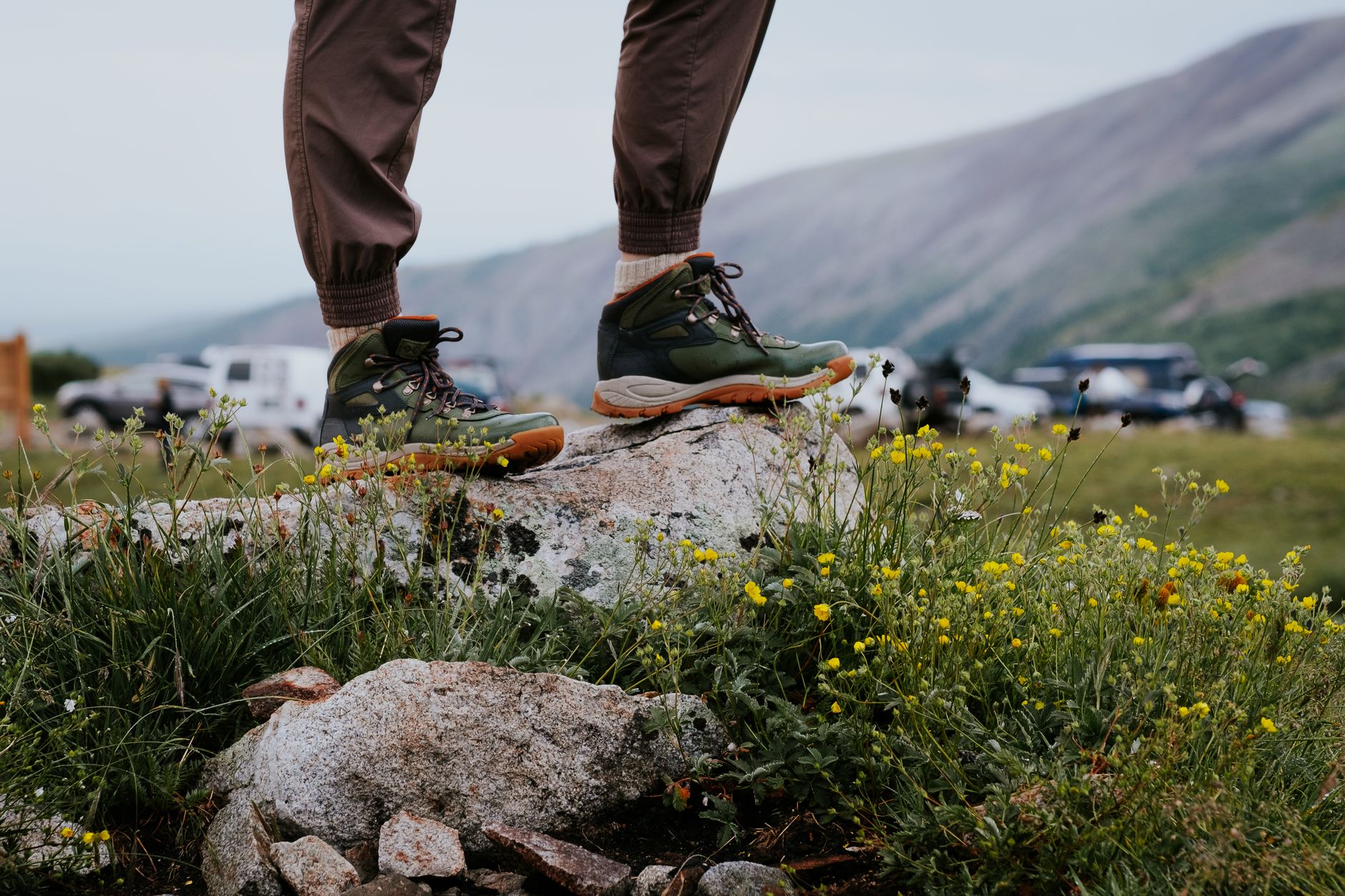 Close-up of hiking boots on a rocky outcrop surrounded by wildflowers in Alma, Colorado.