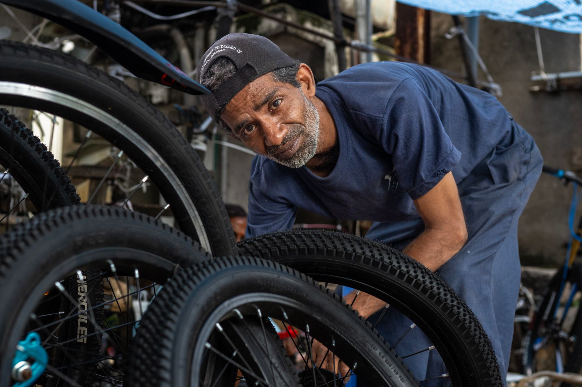 Skilled bicycle mechanic inspecting bike tire in a bustling urban workshop.