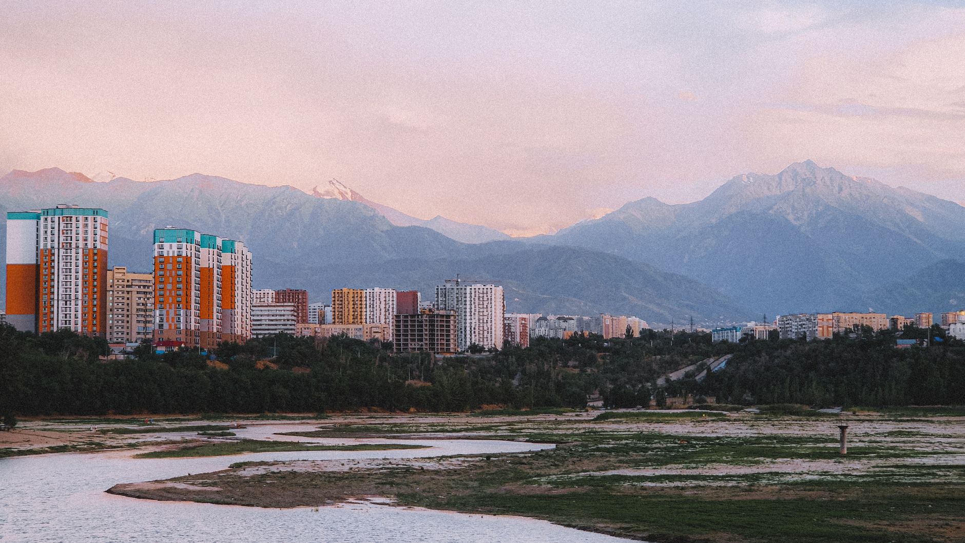 A stunning view of Almaty skyline with mountains in the background at sunset.