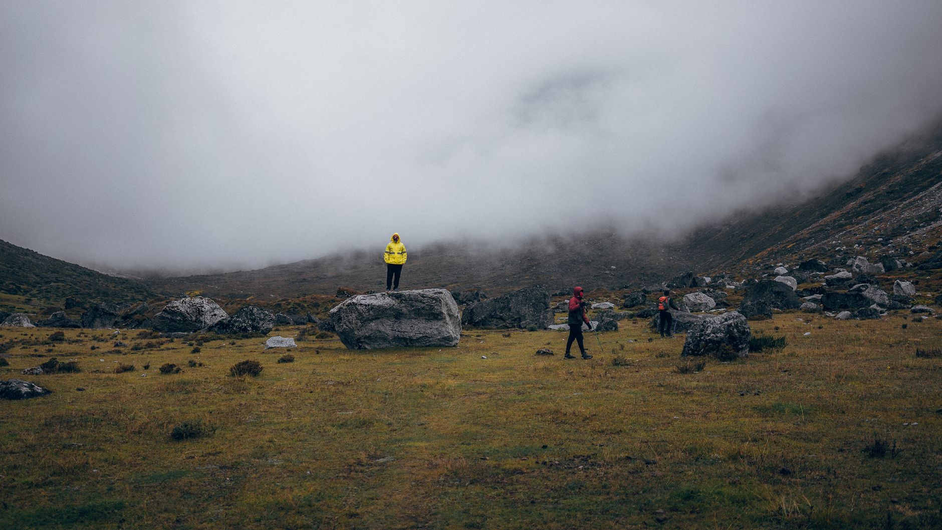 Hikers explore the misty grasslands of Gauri Sankar, Nepal, surrounded by rocky terrain and fog.