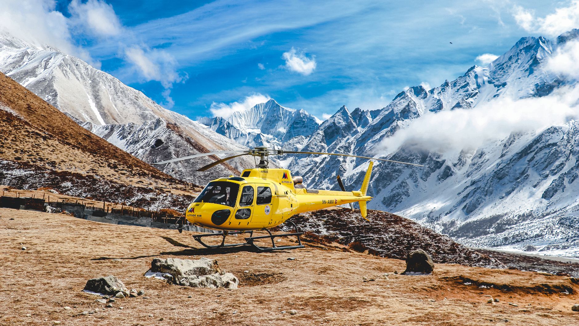 A vibrant yellow helicopter on a snowy mountain in Langtang, Nepal.