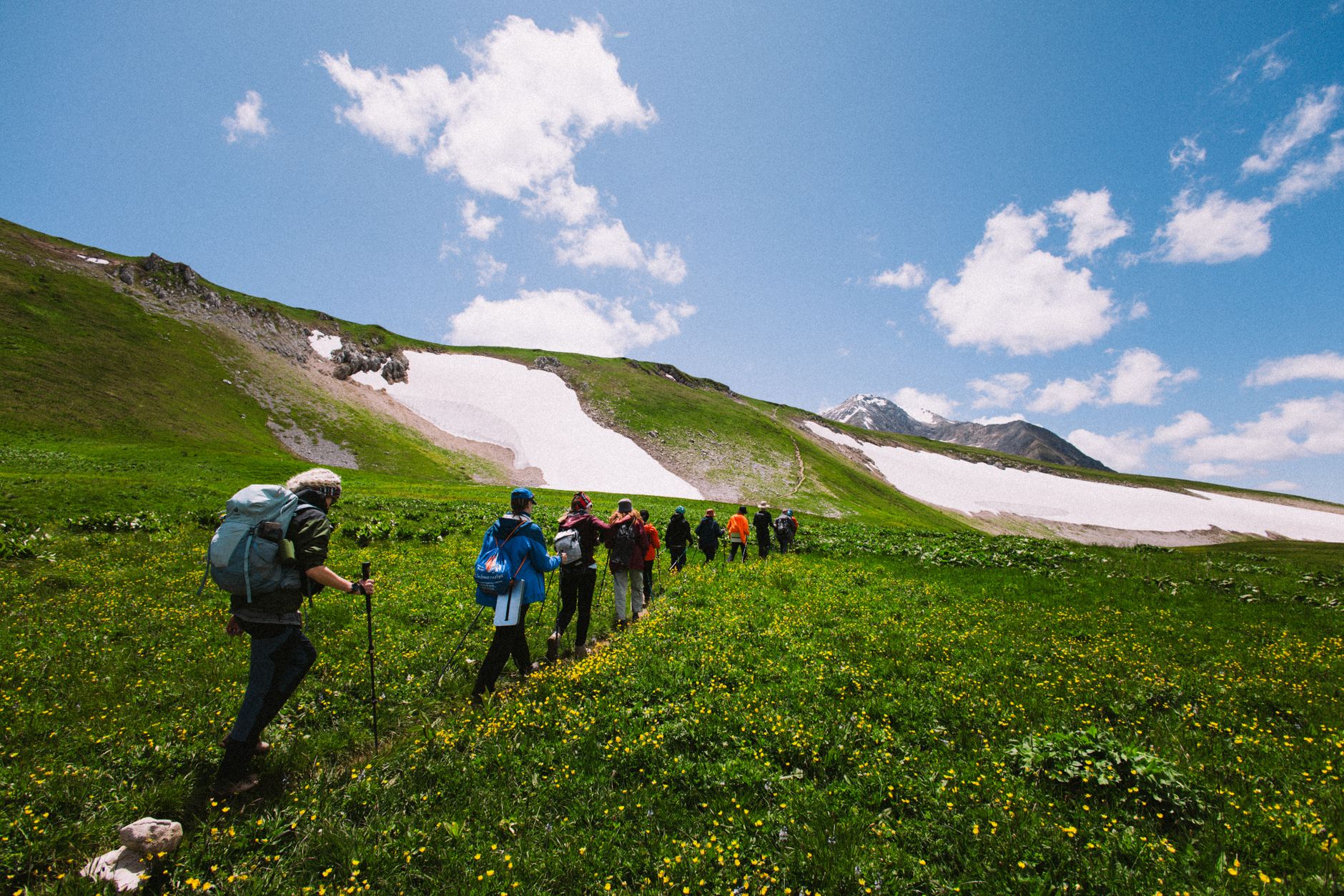 A group of hikers exploring a lush green mountain landscape on a sunny day.
