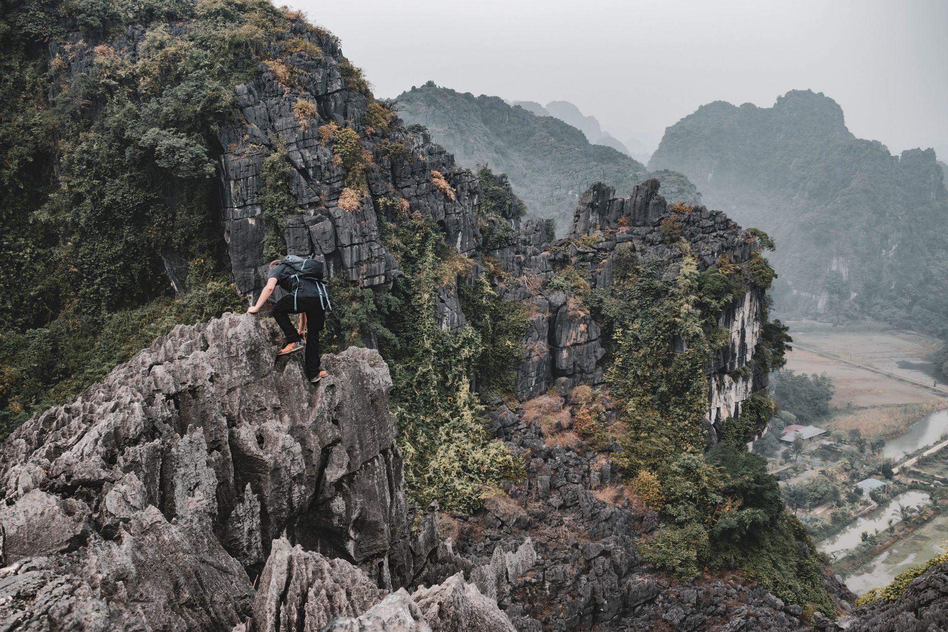 A hiker scales rugged limestone karsts in Hoa Lư, Vietnam, showcasing breathtaking natural beauty.