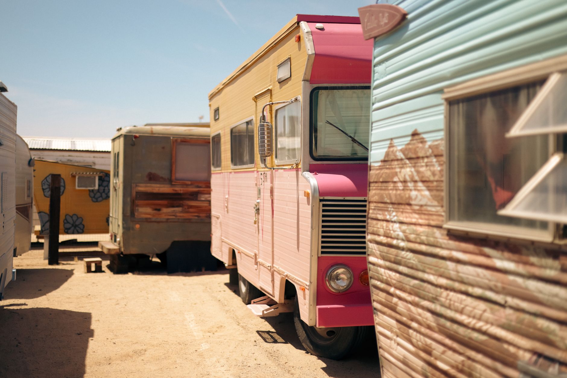 A row of vintage campers under a clear sky in Joshua Tree, California.