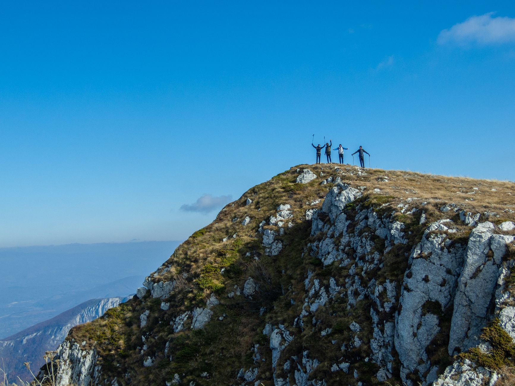 Group of hikers celebrating at the peak of a mountain under a clear blue sky in Belgrade, Serbia.