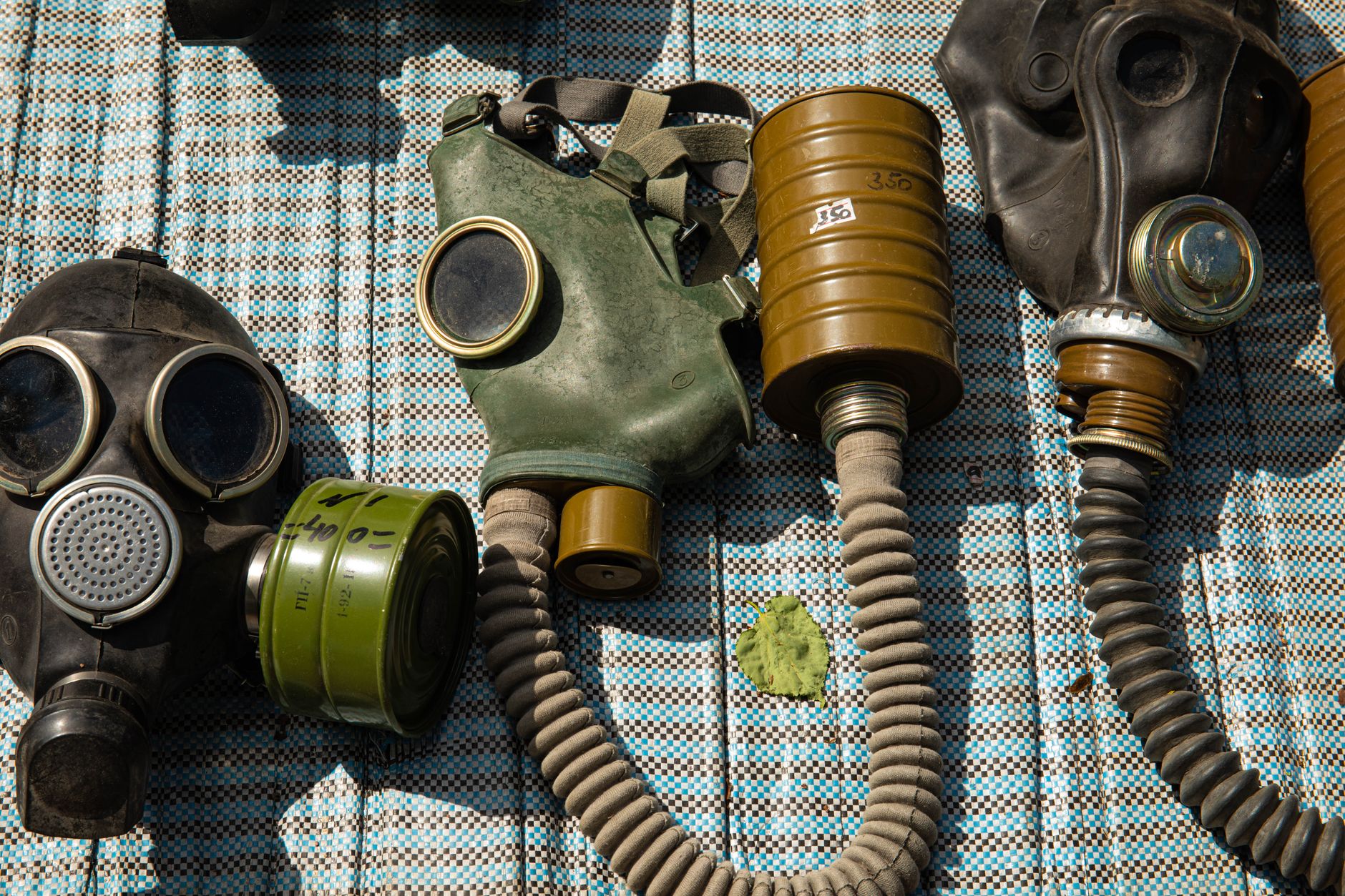 Collection of vintage gas masks placed on a patterned surface, highlighting safety and protection themes.