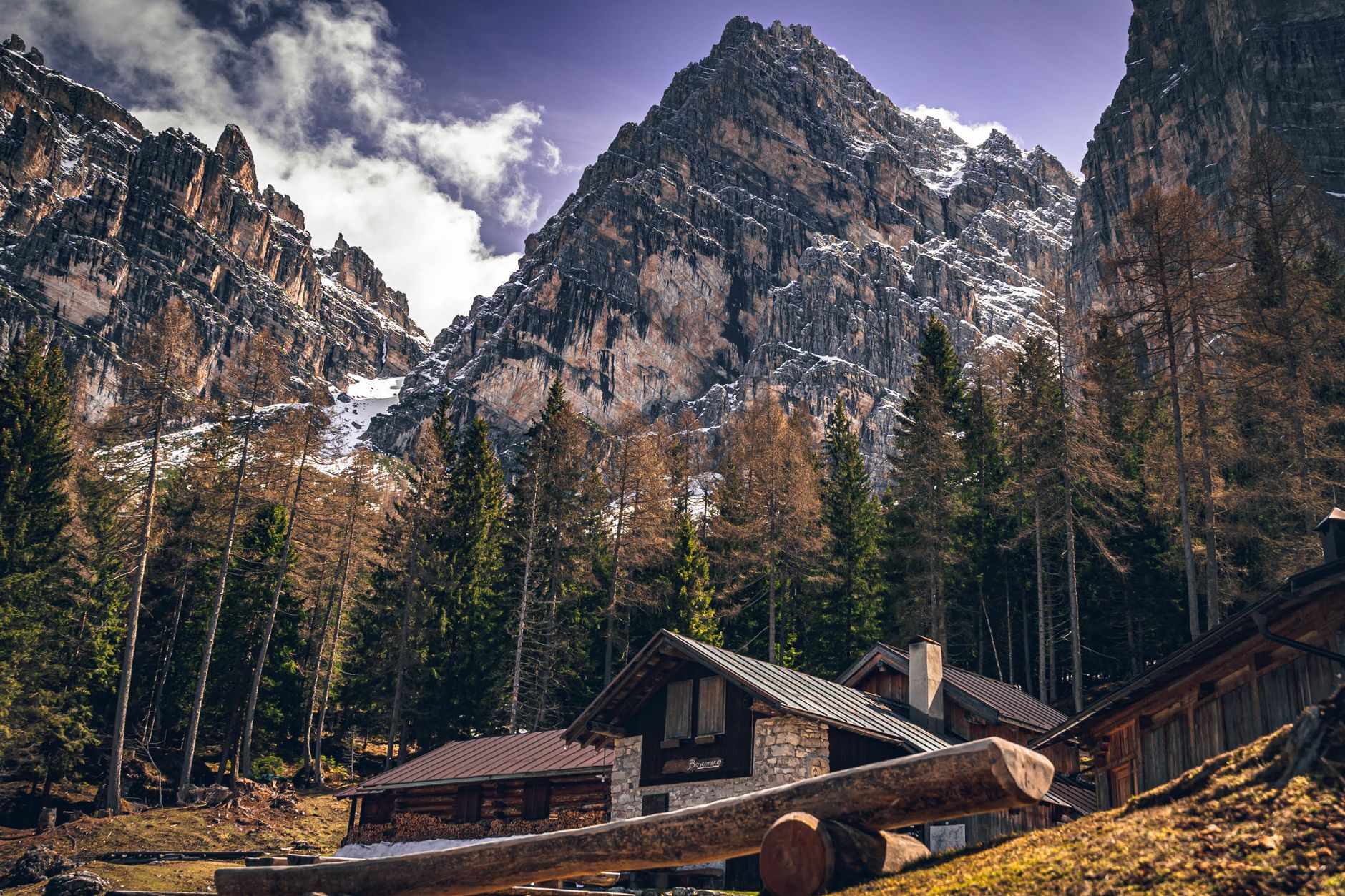 Charming wooden cabins nestled in a picturesque alpine landscape with towering mountains.