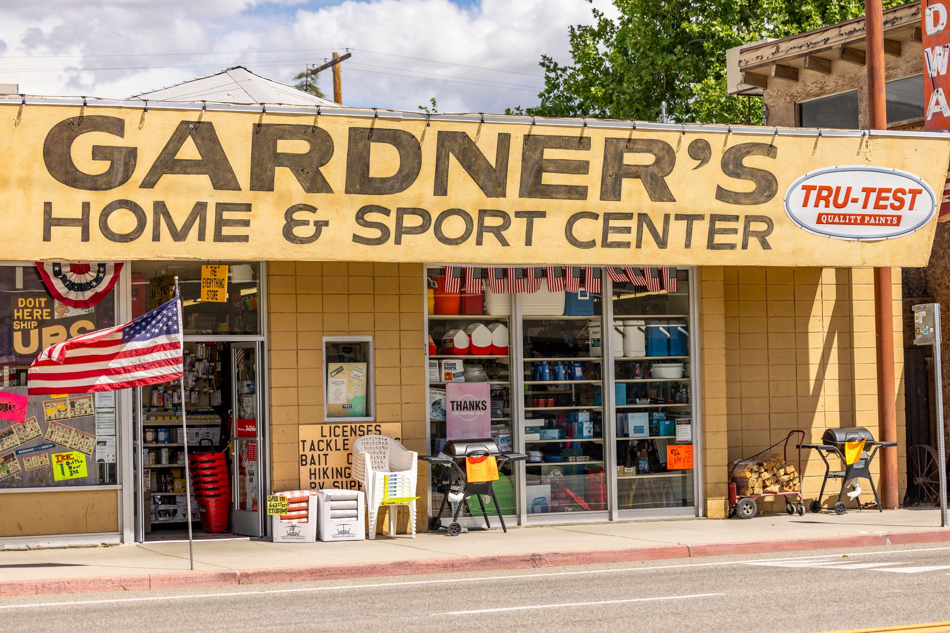 Front view of Gardner's Home & Sport Center with American flag and outdoor displays.
